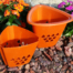 Two orange plastic planters with triangular patterns placed on rocky ground.